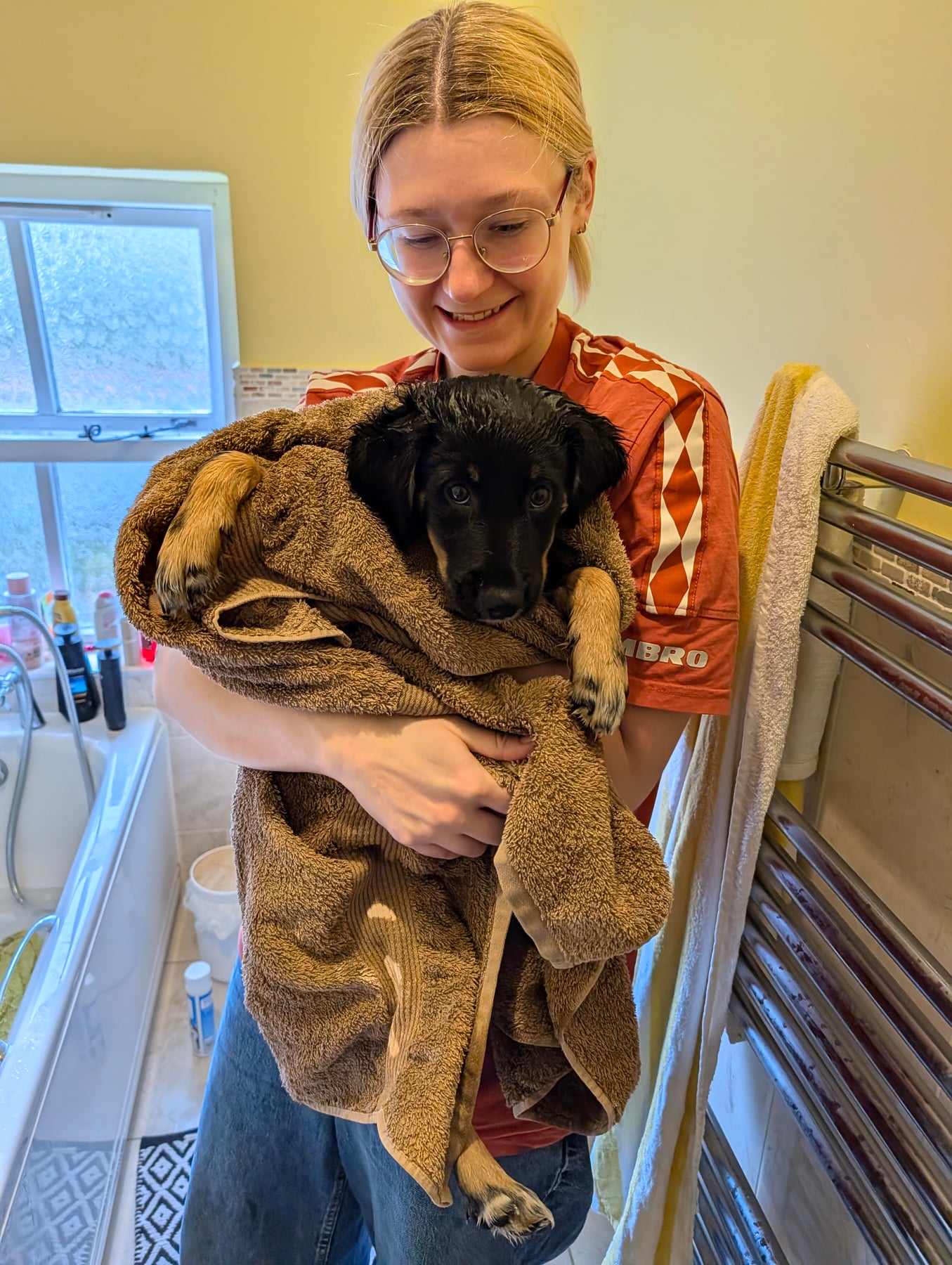 Annie wrapped up in a brown towel after a bath, wet face poking out, being held up to the camera